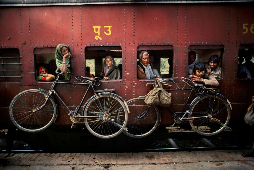 Bicycles on the side of a train, West Bengal, India, 1983 Within a single frame McCurry presents us with four portraits (one could almost say 'character studies') of these travelers. Who knows what each of these individuals are feeling? Where they are going? Who will meet them at the end of their journey? As the bikes hung on the side of the train indicate, maybe for some the journey will continue that little bit further.  Phaidon, Iconic Images, final book_iconic, iconic photographs The Imperial Way_Book Iconic_Book Untold_book final print_UrbanArt'12 retouched_Sonny Fabbri 5/24/2013